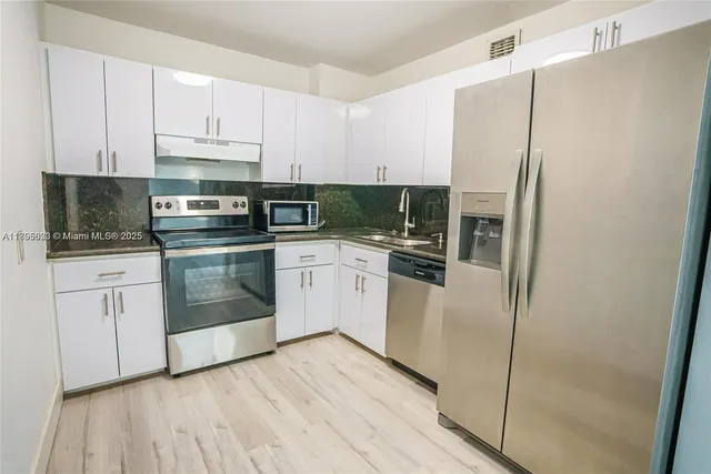 a kitchen with stainless steel appliances white cabinets and wooden floors