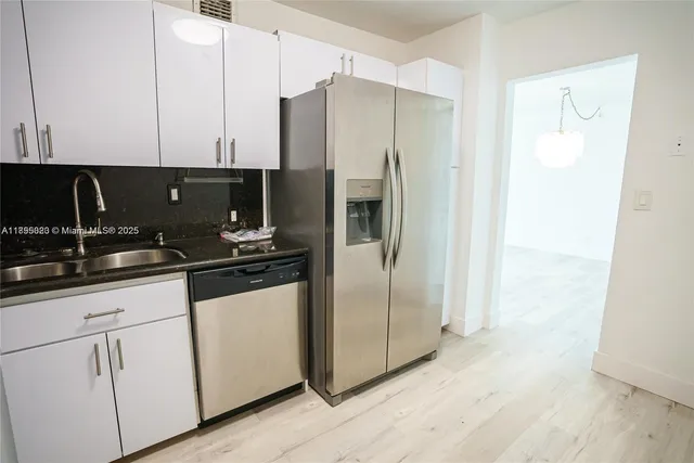 a kitchen with stainless steel appliances a refrigerator a sink and cabinets