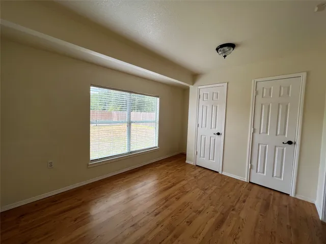 an empty room with wooden floor and windows