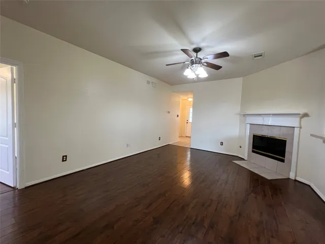 an empty room with wooden floor and a ceiling fan