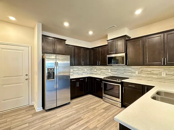 a kitchen with stainless steel appliances granite countertop a sink stove and refrigerator