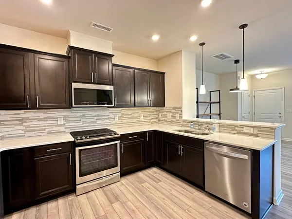 a kitchen with stainless steel appliances kitchen island granite countertop a stove and a sink