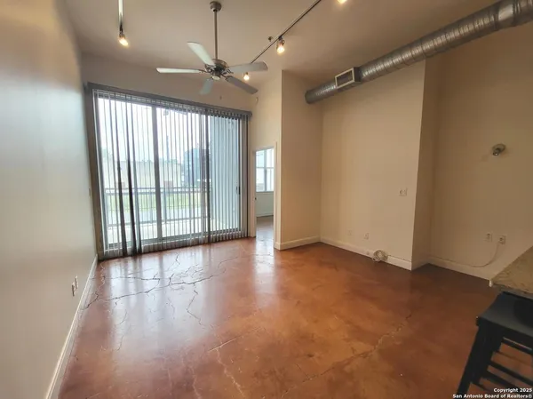 an empty room with wooden floor fan and windows