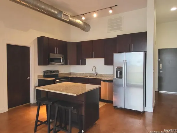 a kitchen with stainless steel appliances a refrigerator a stove a sink dishwasher and a refrigerator with wooden floor