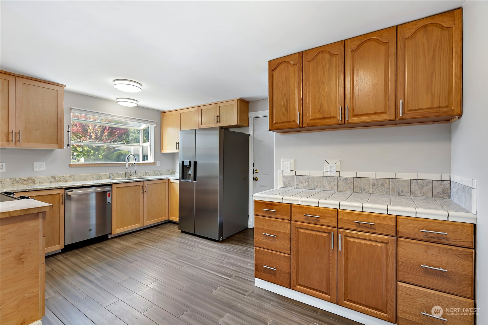 7209 6th Avenue West Everett, WA 98203 - Photo 5 of 27 a kitchen with stainless steel appliances granite countertop wooden cabinets a refrigerator a sink and dishwasher with wooden floor