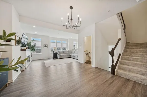 a view of a livingroom with furniture wooden floor staircase and a kitchen view