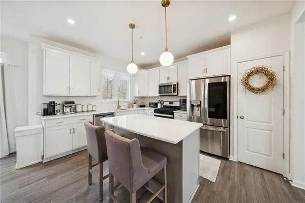 a kitchen with a refrigerator a white cabinets and wooden floor