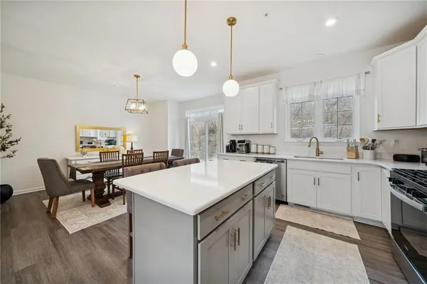 a kitchen with a stove a sink a dining table and chairs with wooden floor
