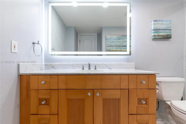 a bathroom with a granite countertop sink a toilet and shower