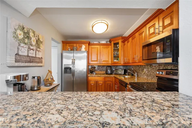 a kitchen with stainless steel appliances granite countertop a stove a refrigerator and a microwave