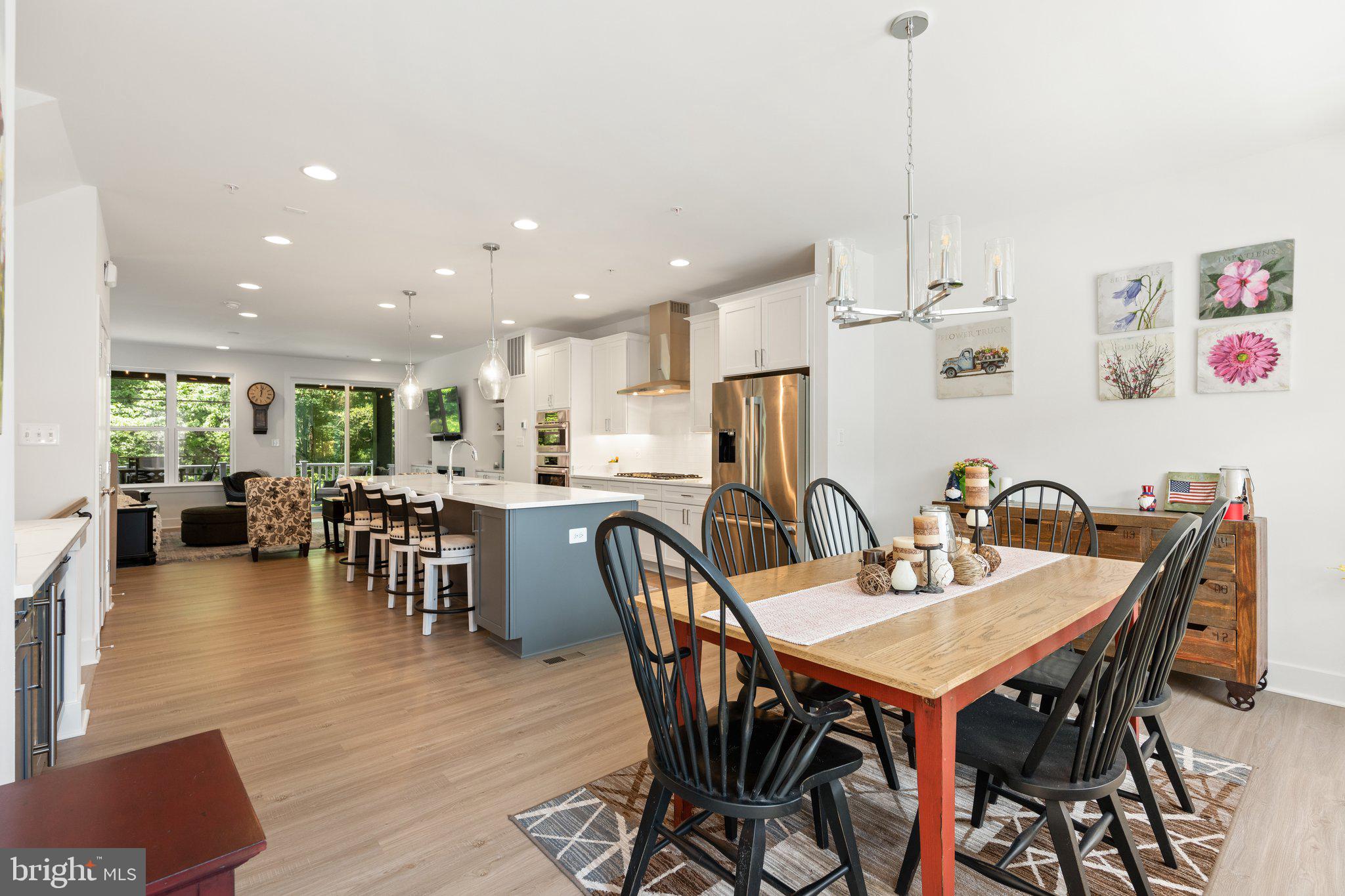 302 Alluvium Drive Laurel, MD 20724 - Photo 15 of 66 a view of a dining room and livingroom with furniture wooden floor a rug a flat screen tv a painting and a chandelier