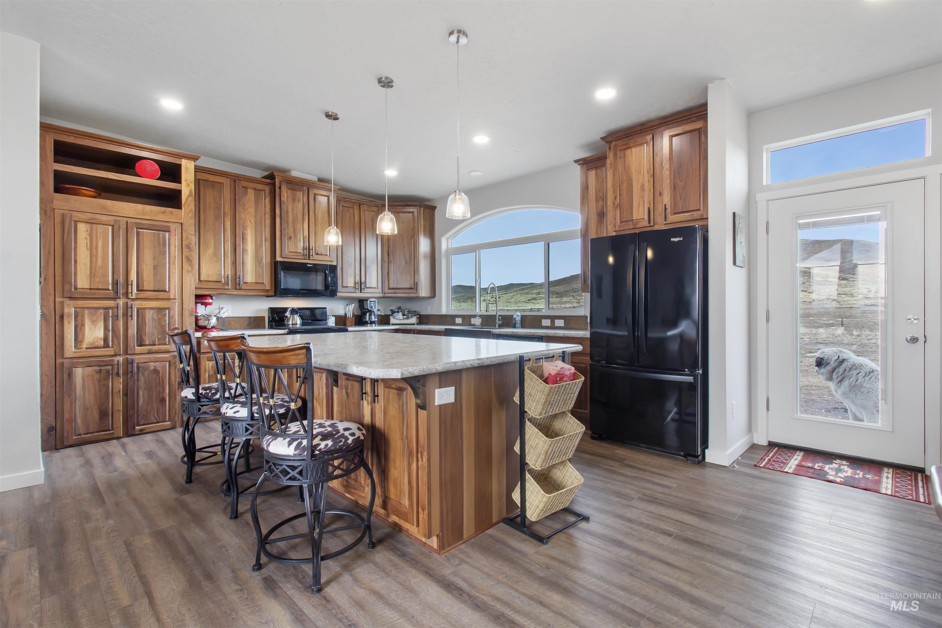 161 Horseshoe Loop West Fairfield, ID 83327 - Photo 14 of 50 Kitchen featuring wood finish cabinets, hanging light fixtures, a center island, black appliances, and a breakfast bar