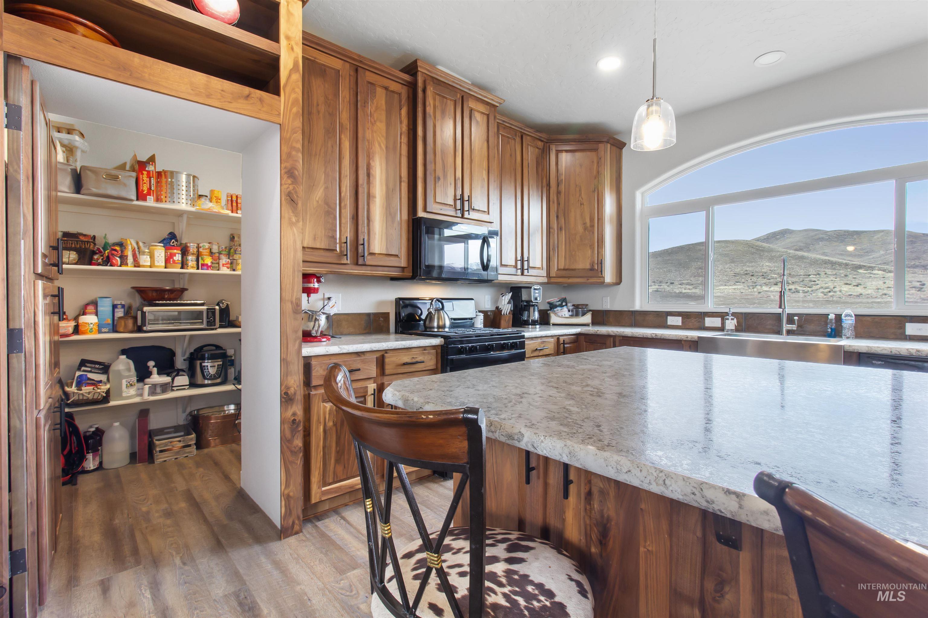 161 Horseshoe Loop West Fairfield, ID 83327 - Photo 20 of 50 Kitchen featuring wood finish cabinetry, black appliances, a mountain view, and pendant lighting