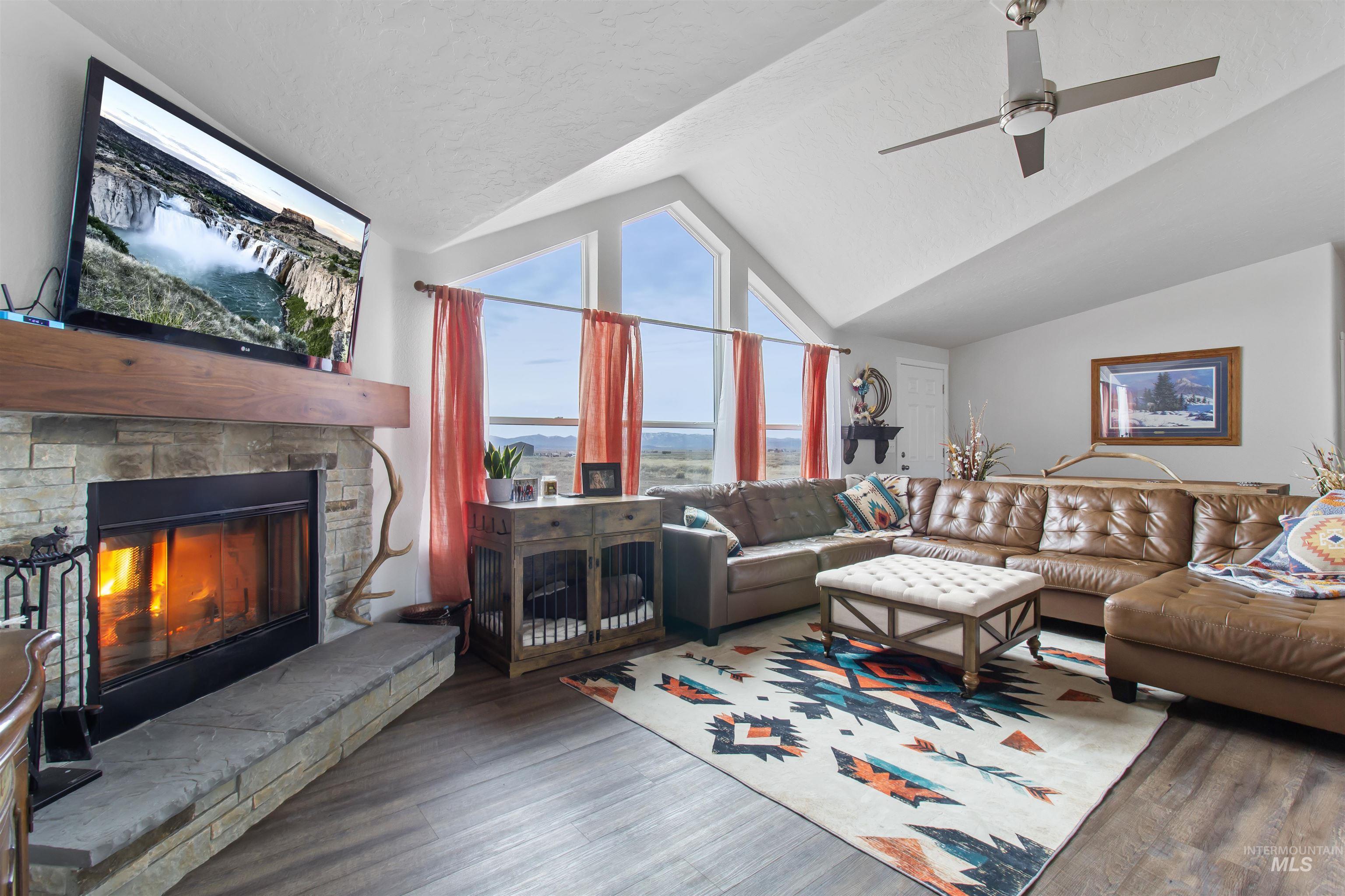 161 Horseshoe Loop West Fairfield, ID 83327 - Photo 24 of 50 Living room featuring wood finished floors, a stone fireplace, and ceiling fan