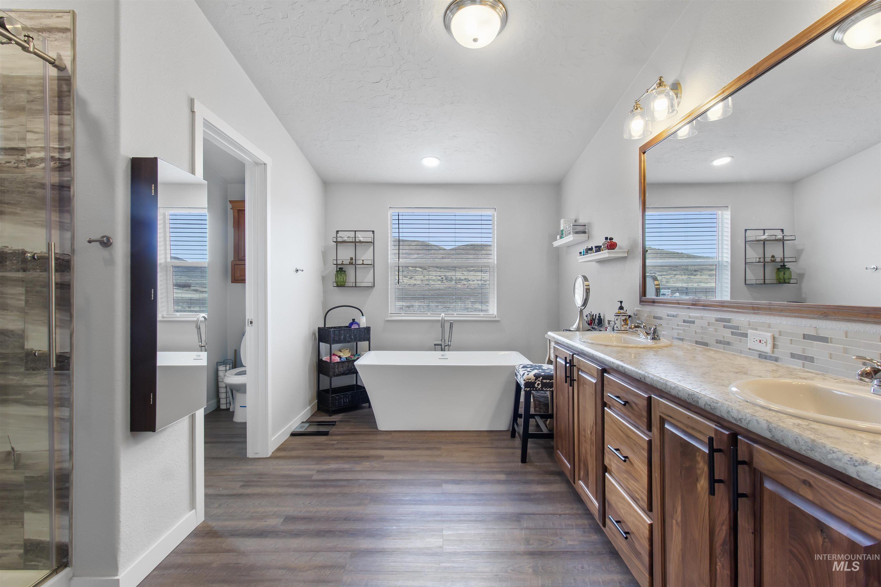 161 Horseshoe Loop West Fairfield, ID 83327 - Photo 30 of 50 Bathroom featuring double vanity, decorative backsplash, dark wood-style floors, a freestanding tub, and a shower stall