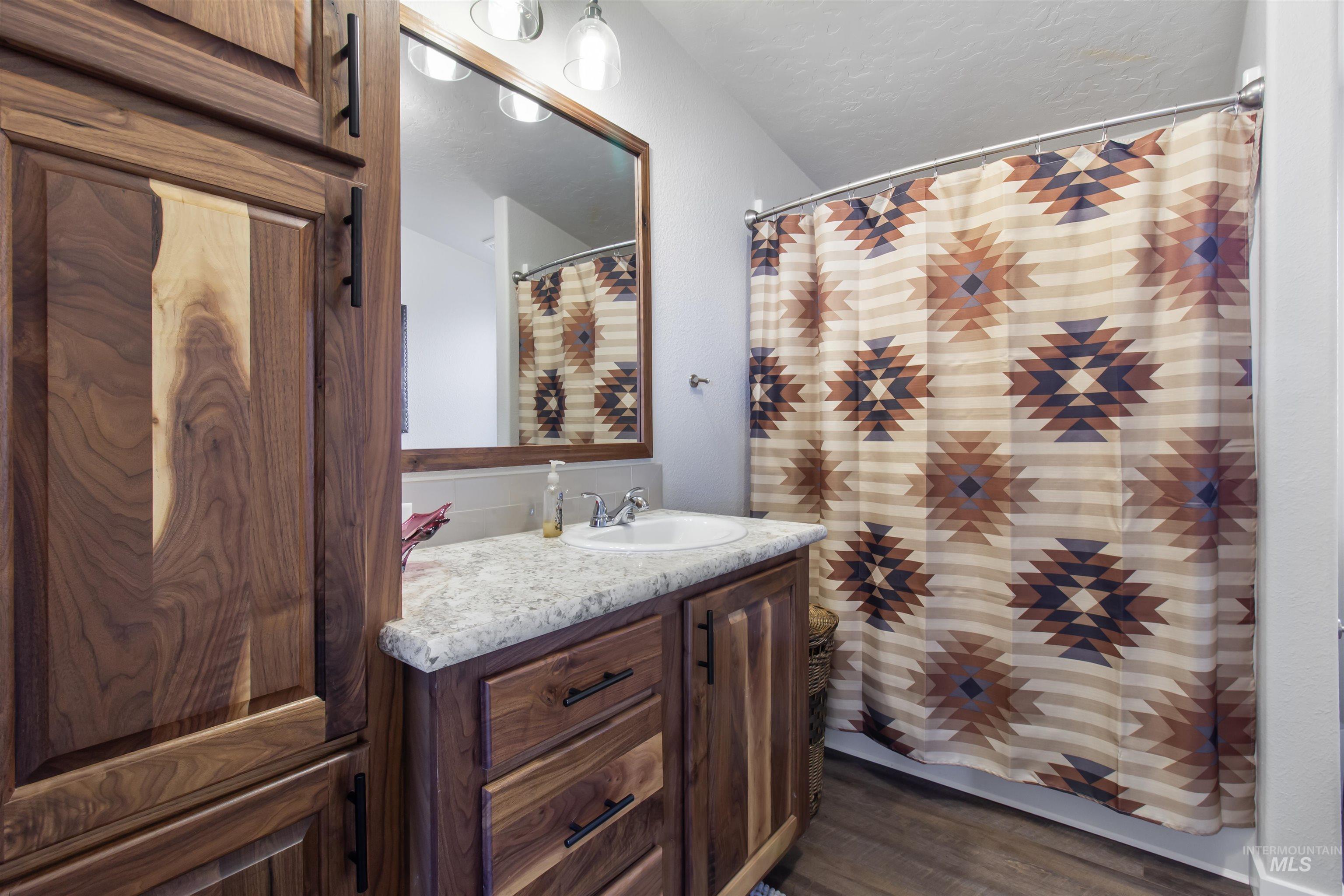 161 Horseshoe Loop West Fairfield, ID 83327 - Photo 36 of 50 Bathroom featuring vanity, a shower with curtain, dark wood-style floors, and a textured ceiling
