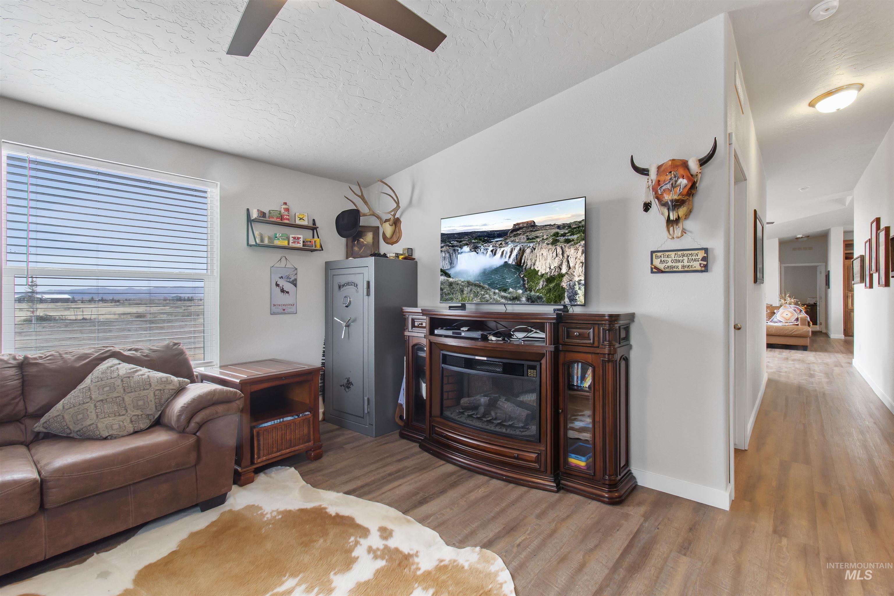 161 Horseshoe Loop West Fairfield, ID 83327 - Photo 10 of 50 Living area with a glass covered fireplace, wood finished floors, and a ceiling fan