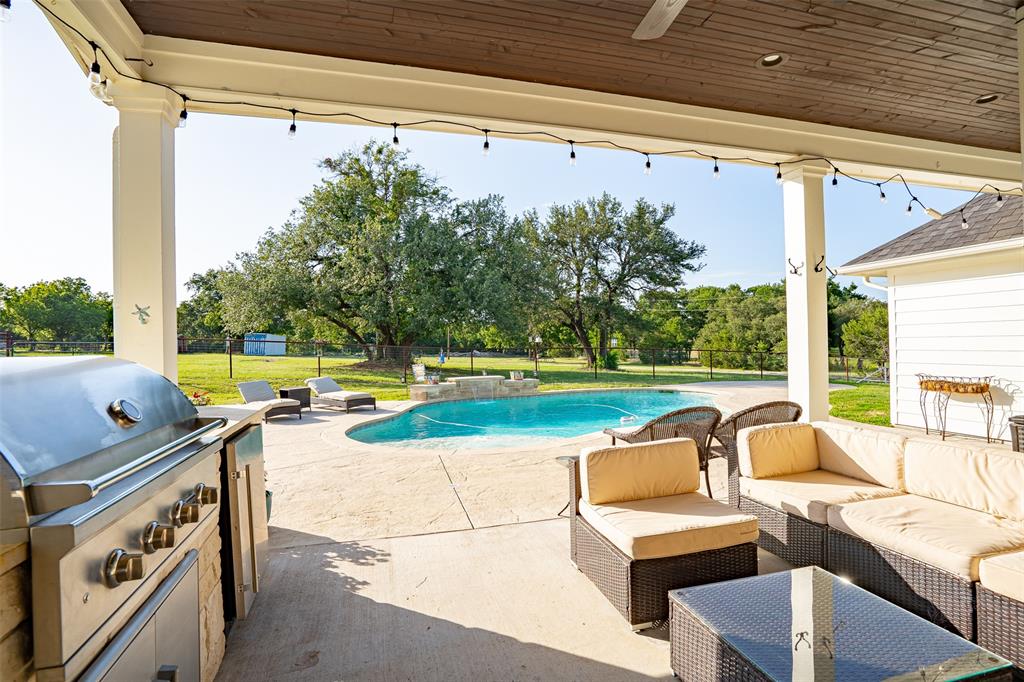 1920 Meander Road Granbury, TX 76049 - Photo 28 of 40 Expansive covered patio featuring an outdoor kitchen with built-in grill, a ceiling fan, and string lighting