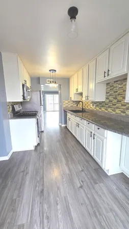 a kitchen with stainless steel appliances wooden floors and view living room