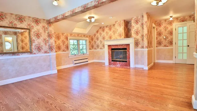 a view of a big room with wooden floor fire place and windows
