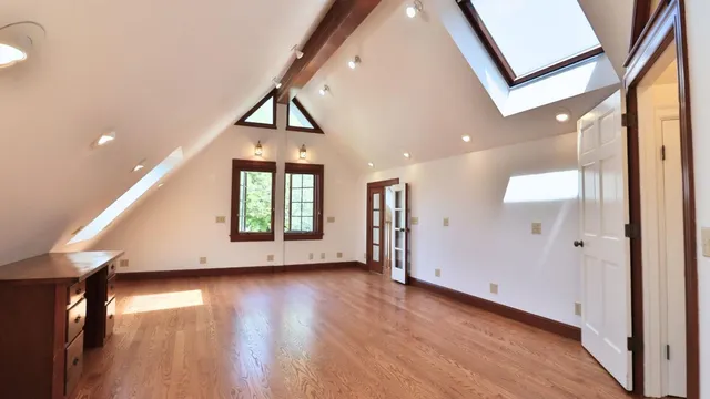 a view of a big room with wooden floor fire place and windows