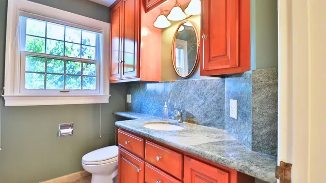 a bathroom with a granite countertop toilet sink and mirror