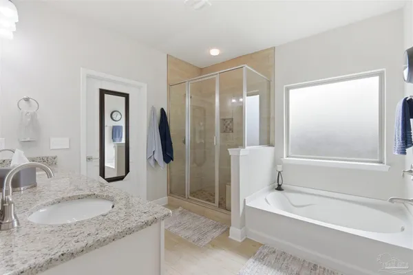 a bathroom with a granite countertop tub sink and mirror