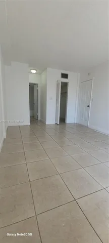 a view of an empty room with closet and a window