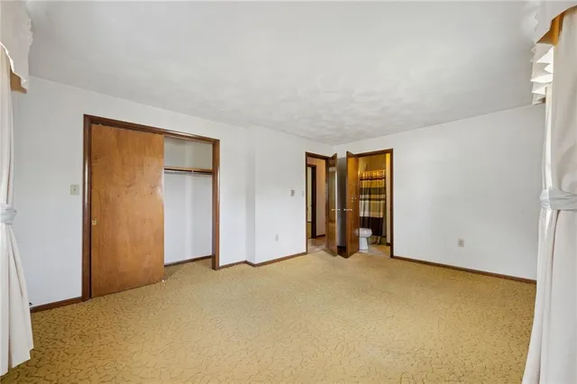 a view of an empty room with closet and a window