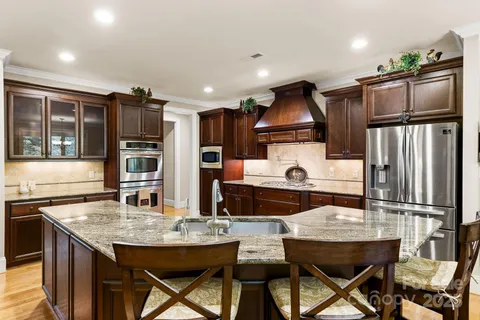 a kitchen with granite countertop a table chairs stainless steel appliances and cabinets