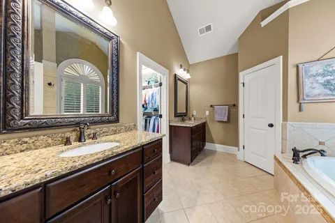 a spacious bathroom with a granite countertop tub sink and mirror