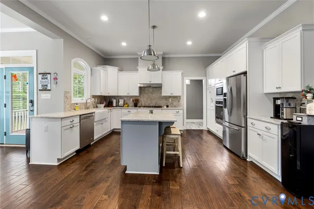 a kitchen with stainless steel appliances kitchen island granite countertop a refrigerator a stove top oven a sink dishwasher and a dining table with wooden floor