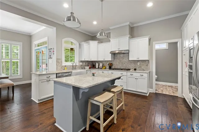 a kitchen with a sink stove cabinets and wooden floor