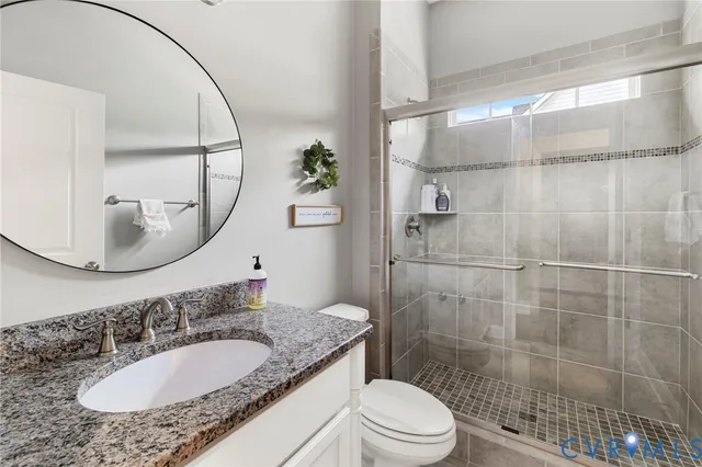 a bathroom with a granite countertop sink a toilet and a mirror
