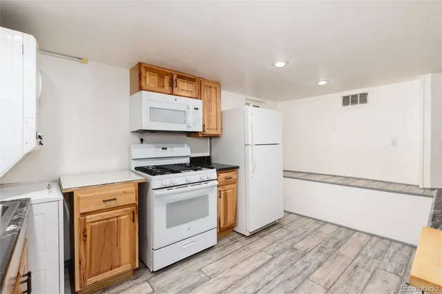 a kitchen with granite countertop a refrigerator a stove a sink and white cabinets with wooden floor