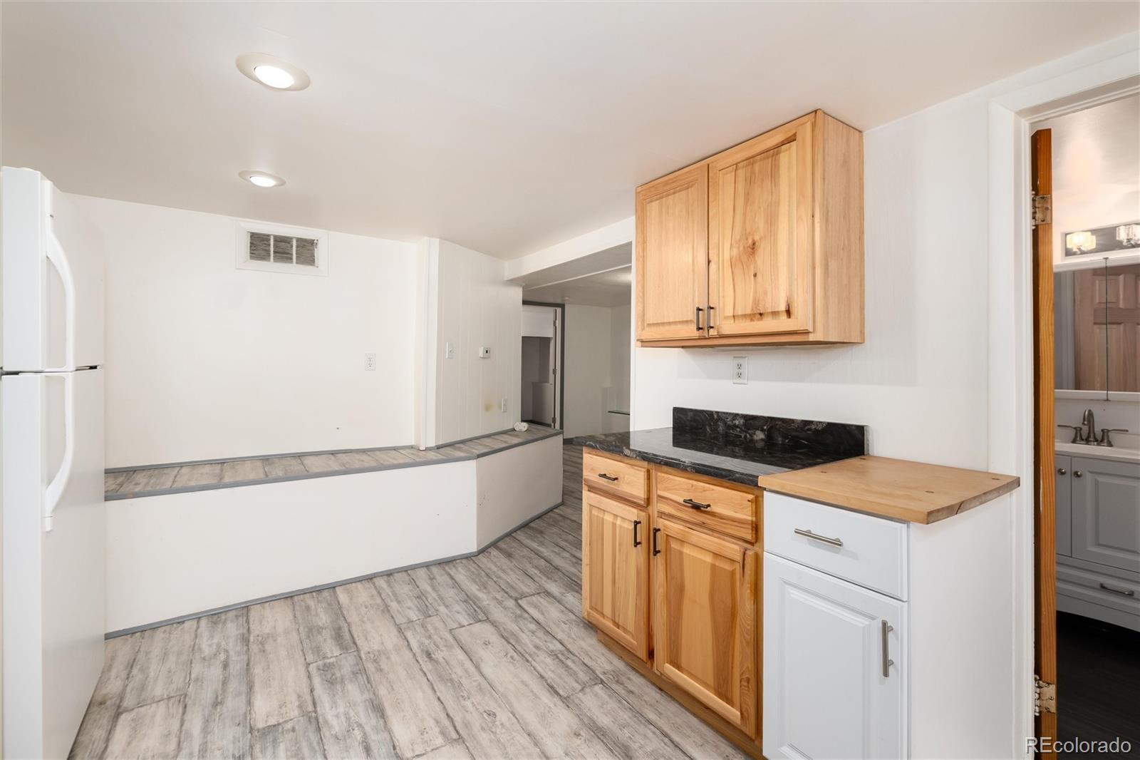 735 Colorado Boulevard Idaho Springs, CO 80452 - Photo 20 of 34 a kitchen with granite countertop a refrigerator a stove a sink and white cabinets with wooden floor