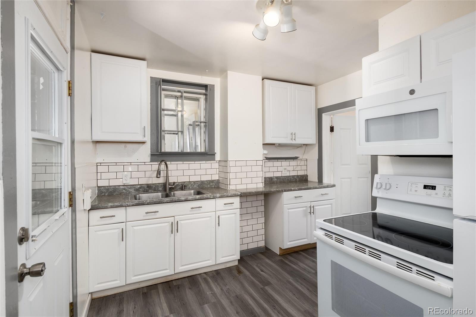 735 Colorado Boulevard Idaho Springs, CO 80452 - Photo 5 of 34 a kitchen with a sink dishwasher and white cabinets with wooden floor