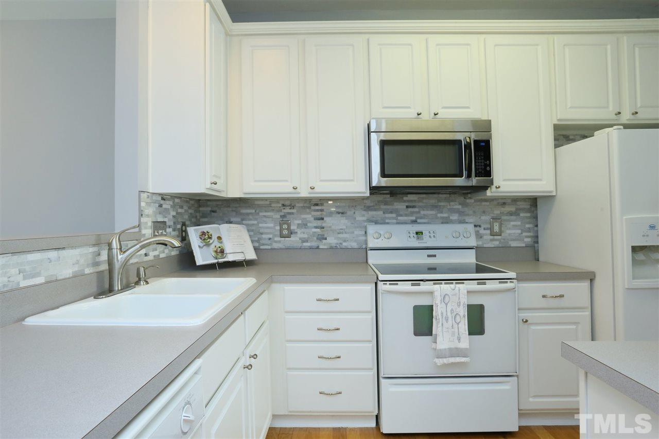 8454 Reedy Ridge Lane Raleigh, NC 27613 - Photo 7 of 30 a kitchen with stainless steel appliances white cabinets and a stove a oven with white countertops