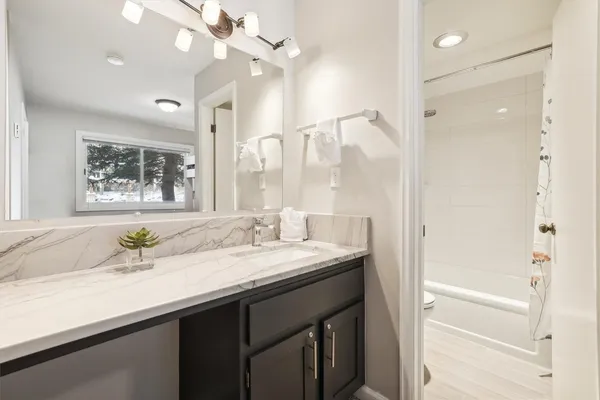 a bathroom with a granite countertop sink a large mirror and a shower