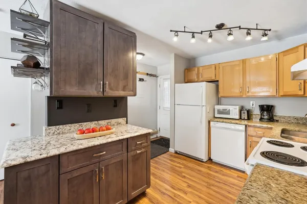 a kitchen with granite countertop a refrigerator stove top oven and cabinets