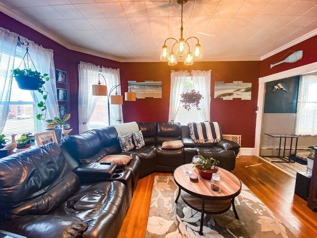 1141 Stafford Road Fall River, MA 02721 - Photo 6 of 30 a living room with furniture a chandelier and a dining table with wooden floor