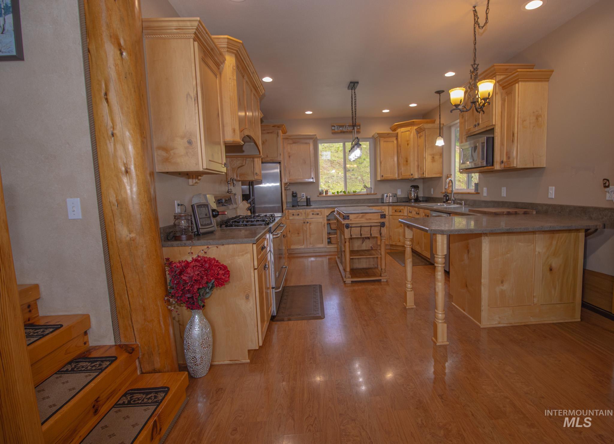 237 Old Dent Road Orofino, ID 83544 - Photo 13 of 48 Kitchen with light wood finish cabinets, a peninsula, stainless steel appliances, pendant lighting, and a kitchen bar