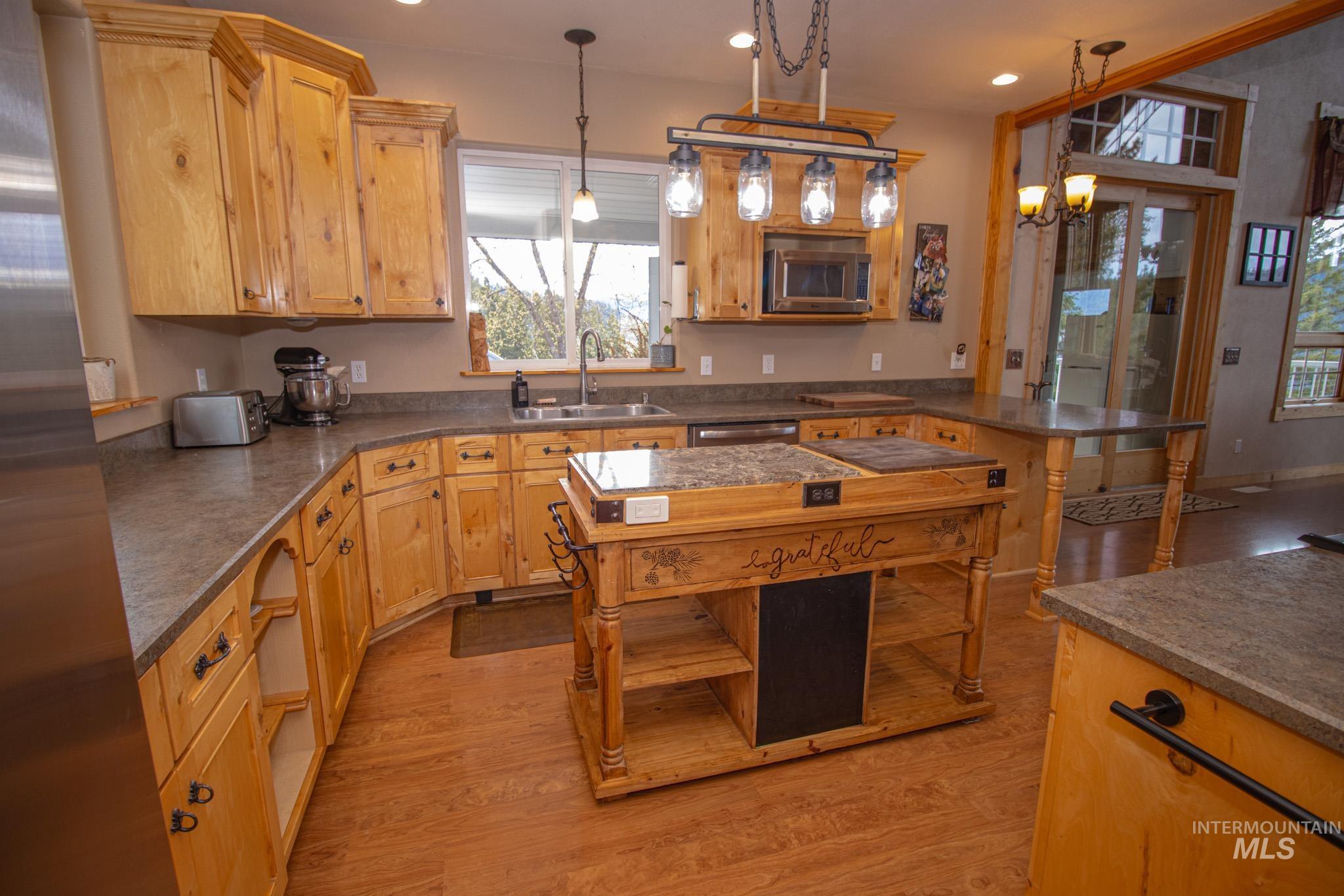 237 Old Dent Road Orofino, ID 83544 - Photo 14 of 48 Kitchen featuring dark countertops, stainless steel appliances, light wood finished floors, and decorative light fixtures