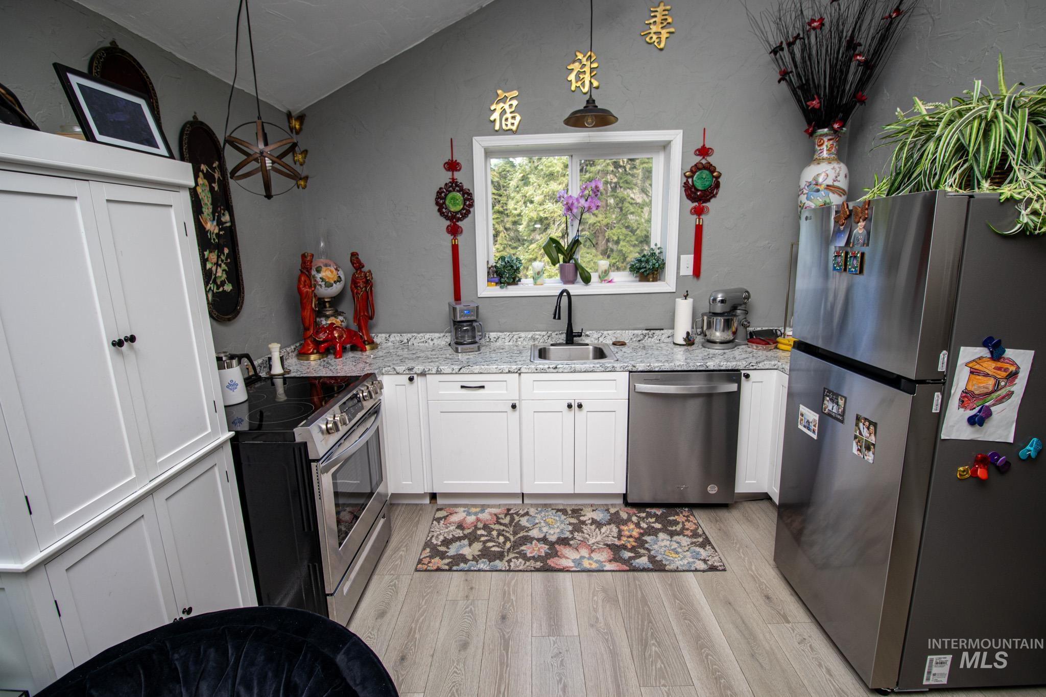 237 Old Dent Road Orofino, ID 83544 - Photo 35 of 48 Kitchen with stainless steel appliances, white cabinets, light stone counters, light wood finished floors, and lofted ceiling