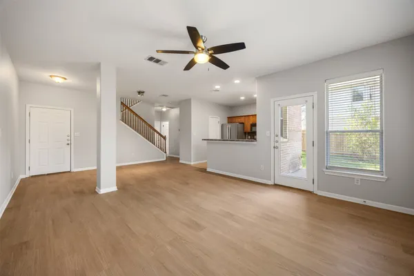 a view of an empty room with wooden floor and a ceiling fan