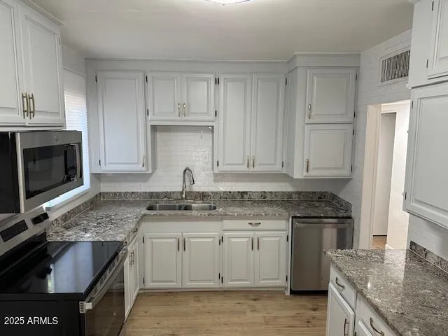 a kitchen with granite countertop a sink stove and cabinets