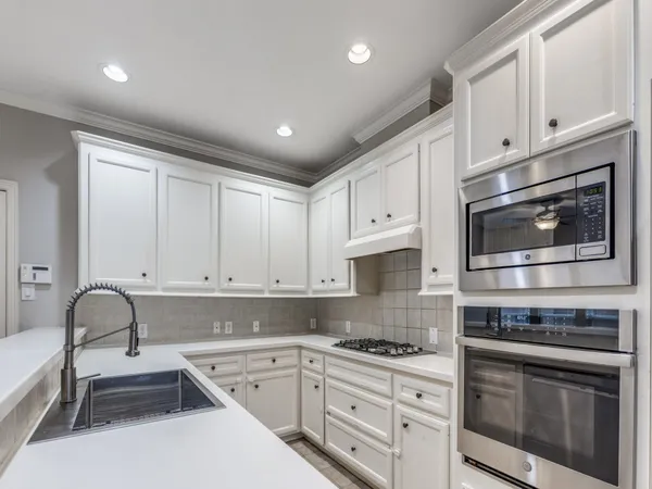 a kitchen with granite countertop white cabinets and stainless steel appliances
