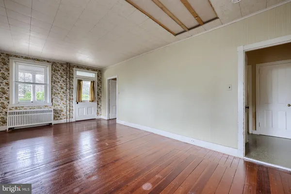 an empty room with wooden floor chandelier fan and windows