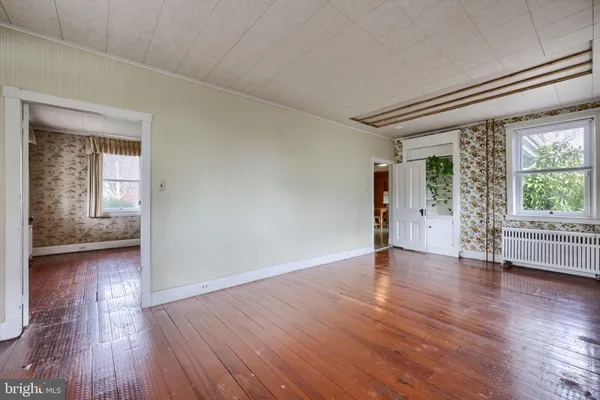an empty room with wooden floor and windows
