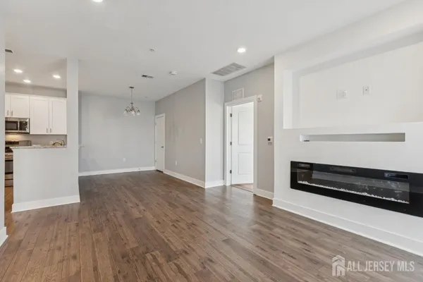 a view of an empty room with wooden floor and cabinets